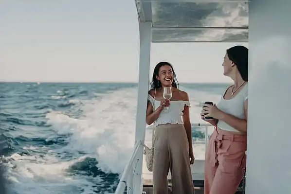 Two people aboard a tour boat enjoying a glass of wine on a sunset cruise around Phillip Island