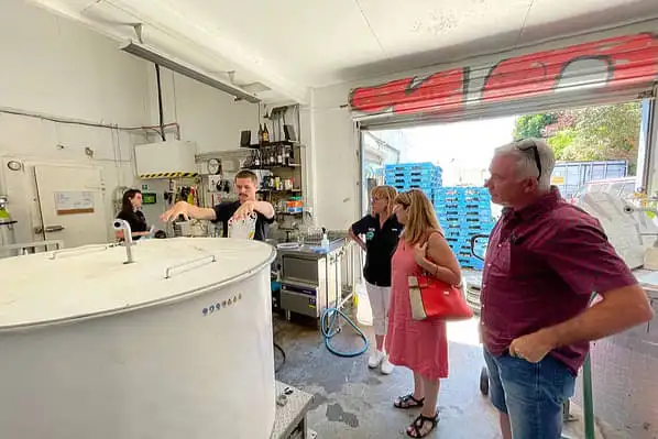 A group of people standing around a beer keg and learning about the brewing process. 
