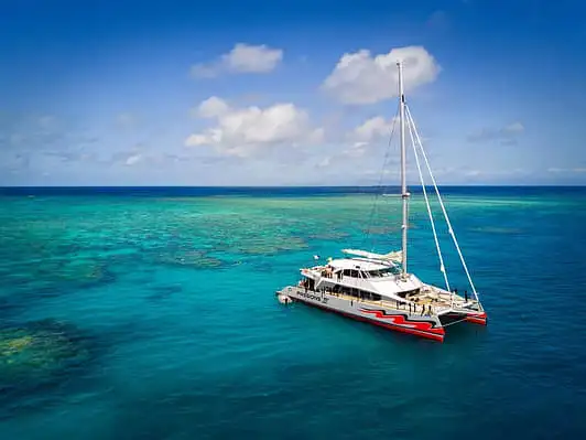 A white catamaran anchored in the turquoise waters of the great barrier reef