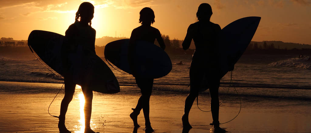 People with surf boards watching sunset in Byron Bay