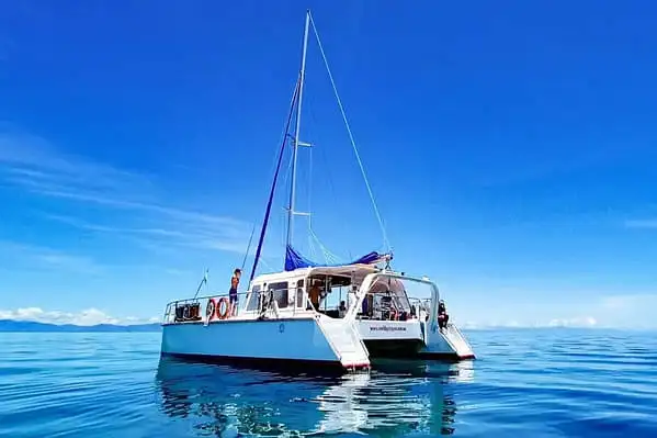 A white catamaran anchored in calm blue waters