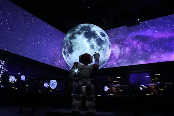 A dark room lit up by projections of the moon and the purple cosmos, located inside South Australia's Museum of Discovery